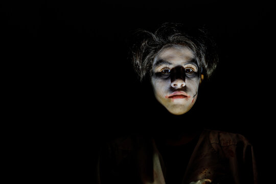 Horror portrait of a teenage girl in the darkness of halloween with dark copy space