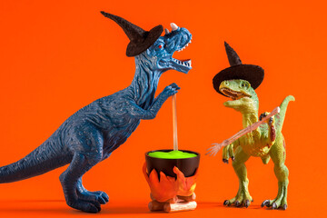 Two funny dinosaurs wearing witch hats are brewing potion in pot on  orange background. Halloween...