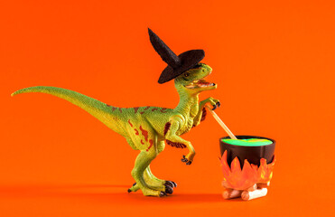 Dinosaur wearing witch hat is brewing potion in pot on orange background. Halloween greeting card.