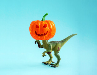 Cute green dinosaur toy with  pumpkin for head. Humor concert Halloween greeting card.
