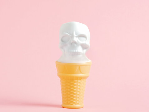 Ice cream in shape of white human skull on waffle cone on pastel pink background. Minimal art Halloween poster.