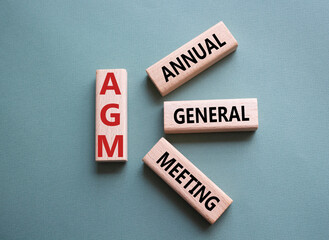 AGM - Annual general meeting symbol. Concept word AGM on wooden cubes. Beautiful grey green...