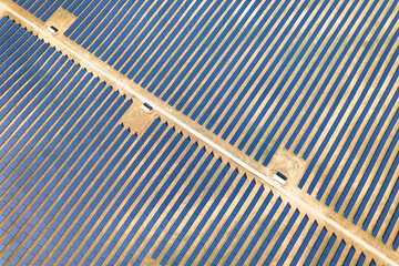Top view of solar panels in a row on the energy farm. Aerial view of futuristic patterns with solar panels on a solar power plant. Industrial background on renewable resources. Photovoltaic complex