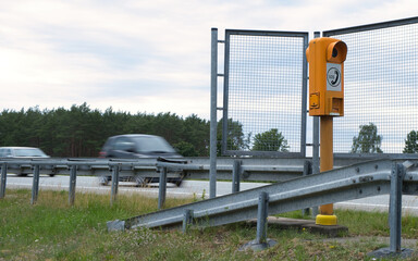 Orange motorway emergency telephone. Fast cars driving by.
