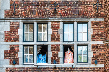 Two open windows in a red brick house, clothes hanging behind