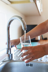 Woman filling a glass of water at the faucet