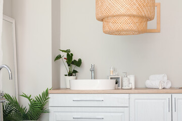 Sink bowl and bath accessories on white counters in bathroom