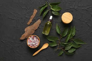 Bottle and jar of cosmetic products with sea salt on black background