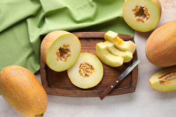 Wooden board with pieces of sweet melon on white background