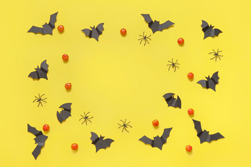 Frame made of pumpkins, paper bats and spiders on yellow background. Halloween celebration concept