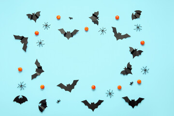 Frame made of pumpkins, paper bats and spiders on blue background. Halloween celebration concept