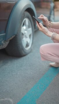 Car accident. Closeup on woman in the city with smartphone near car with flat tire.