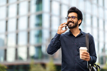 Young eastern businessman talking on phone while walking by street