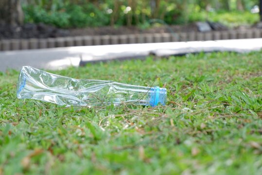 A plastic bottle of drinking water littering on  pathway with green field background,for saving an environmental concept 