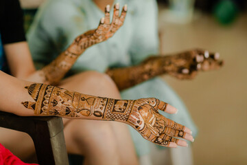 Artist applying henna tattoo on women hands. Mehndi is traditional Indian decorative art.