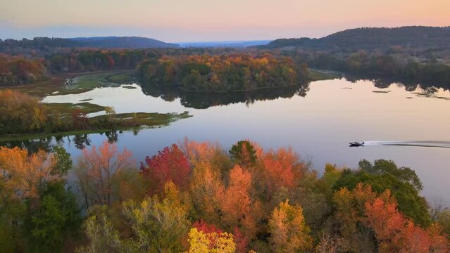 Boat motors over glassy lake reflection during fall with autumn colored country leaves aerial drone shot  