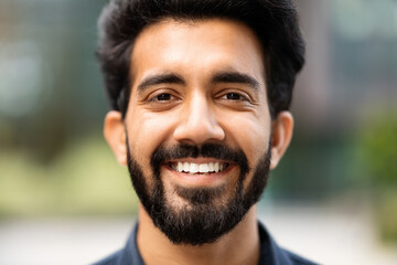 Closeup of happy young eastern man posing on the street