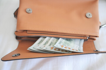 US dollar cash in women purse on bed 