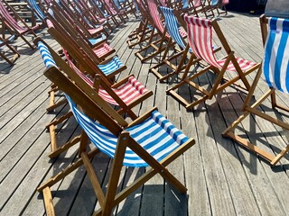 deck chairs on pier wooden striped empty on windy day 