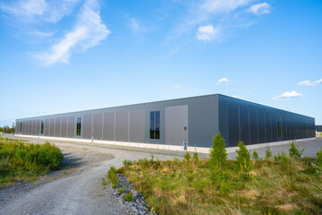 Exterior of a new and large grey warehouse.