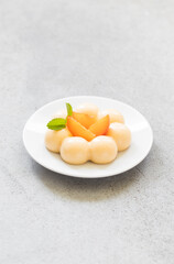 Apricot cream pudding in the shape of truffles, decorated with fresh apricot slices