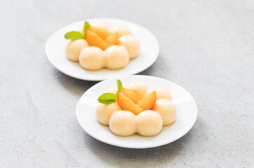 Vegan Apricot cream dessert, Panna Cotta in the shape of truffles, decorated with fresh apricot slices. On a plate. LIght grey background. Close up