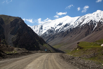 Road in Barskoon gorge, with snow-covered mountains and forest, to Barskoon pass. Kyrgyzstan