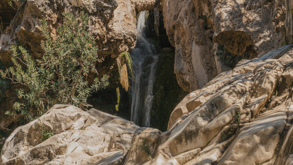 Fototapeta na wymiar Blurred motion of waterfall amidst majestic rock formations in cave