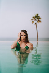 Obraz premium Chica joven posando en piscina de hotel durante sus vacaciones