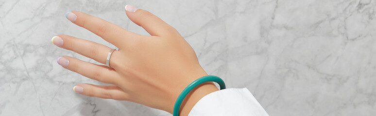 Beautiful womans hand with spring summer nail design on marble gray background