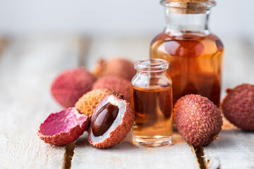 Glass bottles with pure organic essential litchi oil on wooden background. Concept of natural ingredients for beauty treatment, skin care, massage. Exotic fruit extract