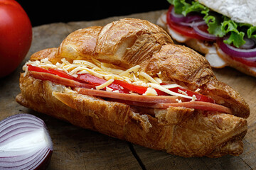 Croissant with ham, cheese and tomatoes on a wooden board. Close-up