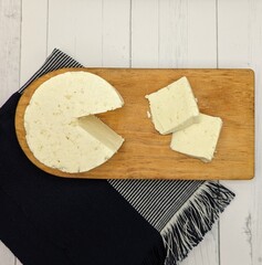 Sliced panela cheese on wooden dish. White wooden table with blue tablecloth