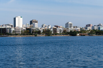 Fototapeta premium View of Rodrigo de Freitas Lagoon, south zone of Rio de Janeiro, Brazil. In the background, Dois Irmãos hill and Pedra da Gávea. Sunny day. Buildings around. Pond water used for sports