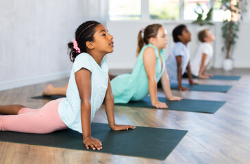 Fototapeta na wymiar Preteen Children practicing yoga in Urdhva Mukha Shvanasana in the gym