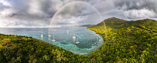 Anchored beneath nature's grand spectacle, boats rest quietly, encircled by the vibrant hues of a...