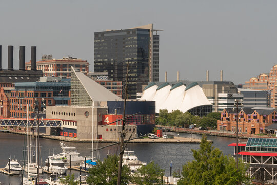 Baltimore, MD US - July 26, 2023: National Aquarium pier 4 building and surrounding urban waterfront architecture , as seen from the top of Federal Hill Park through a long lens