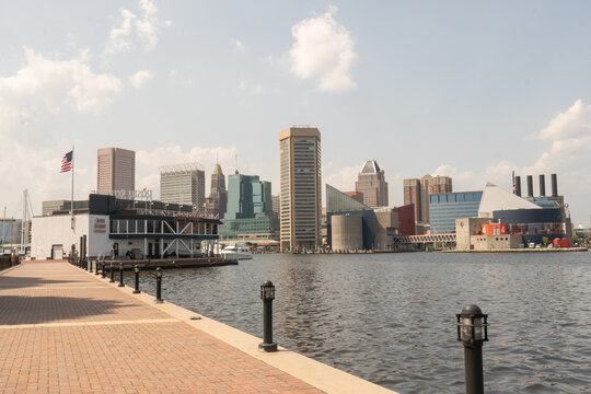 Baltimore, MD US - July 26, 2023: Baltimore Waterfront Promenade views of the Rusty Scupper, Water Taxi stop, and the distant Inner Harbor city skyline including the World Trade Center and Aquarium