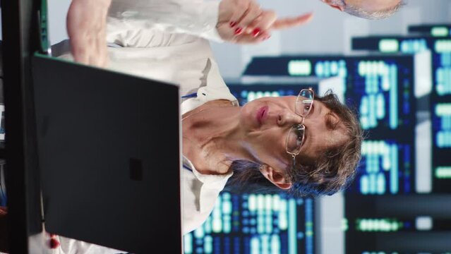 Vertical video Aged coworkers looking around modern server farm, preparing to start comission on malfunctioning high tech workspace hardware clusters in order to ensure proper operations