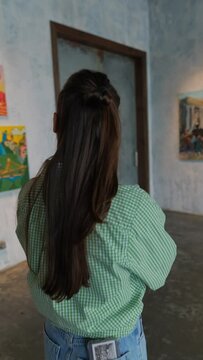 A girl is observing artworks at the art exhibition.