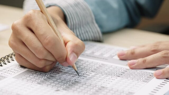 Student take exam choice with hands and write the exam test answer sheet with pencil,Answering test questions on the exam concept