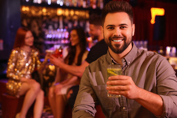 Friends spending time together in bar. Handsome man with fresh alcoholic cocktail, space for text
