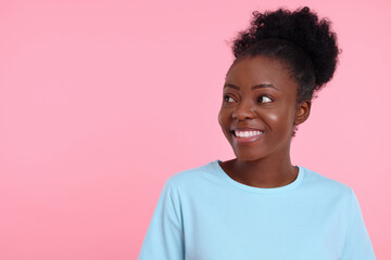 Portrait of happy young woman on pink background. Space for text