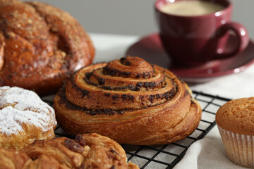 Tasty freshly baked spiral pastry on cooling rack, closeup