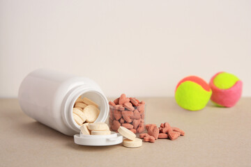 Different pet vitamins and toy balls on beige table, space for text