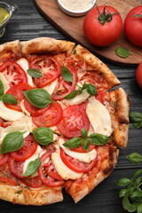 Delicious Caprese pizza on black wooden table, flat lay