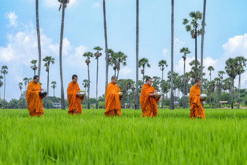 Buddhist monks with good spiritual going about with alms bowl to receive food from people in...