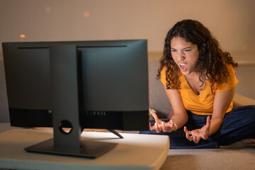 Enraged young woman screaming while watching TV