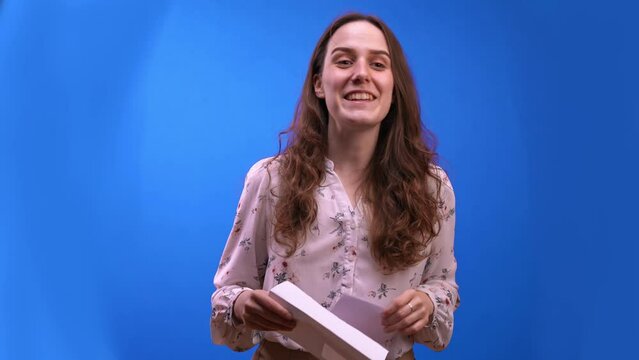 Host woman on blue background opens envelope announcing winner of the competition, looks around in confusion, waiting for the contestant, hitch. Award Ceremony, Presentation of Gifts, Voting Results
