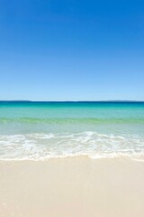 Fototapeta premium Clear turquoise waters, cloudless blue skies, sea foam and white sand on a sunny day at Callala Beach in Shoalhaven — Jervis Bay National Park, New South Wales, Australia
